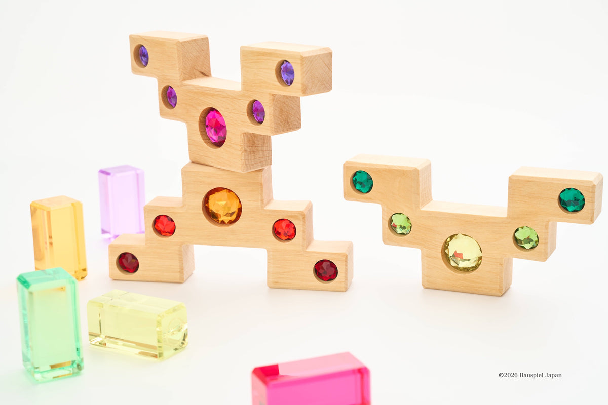 Bauspiel wooden staircase blocks stacked with translucent coloured blocks beside them.