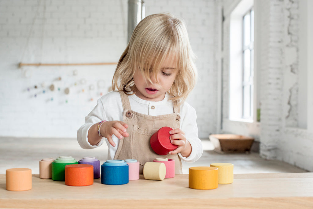 Child exploring Grapat nesting bowls at a table