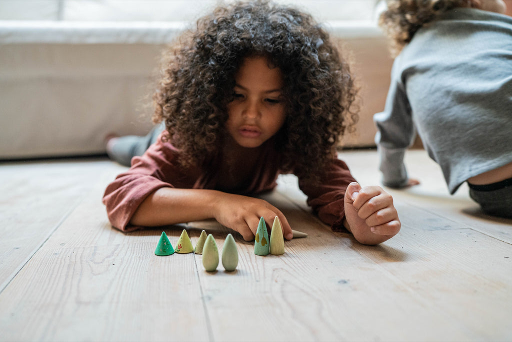 Child arranging Grapat wooden trees on the floor