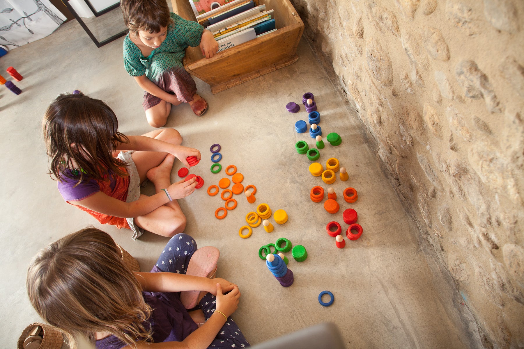 Children arranging Grapat wooden figures, rings and coins in colourful play